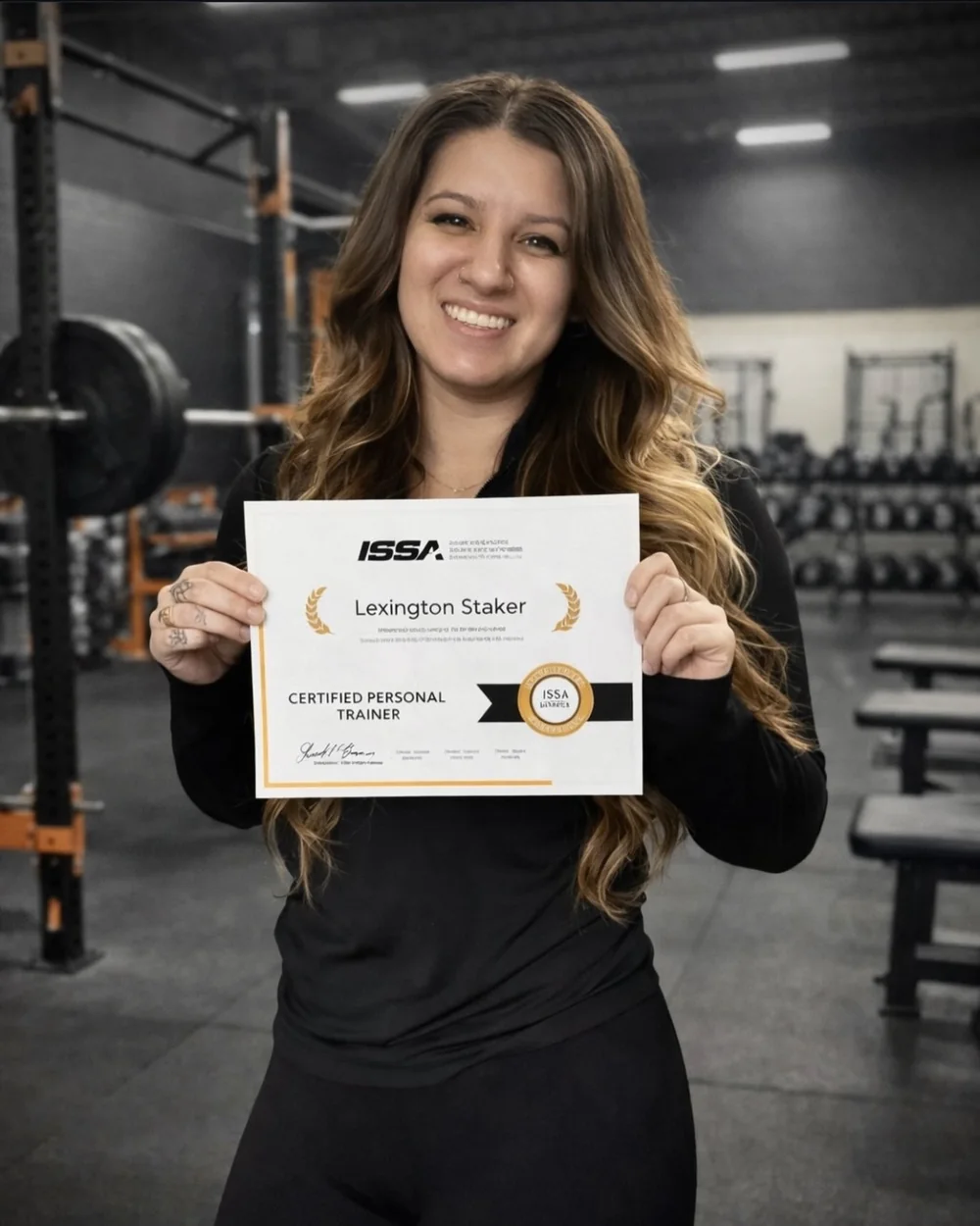 Lexi Staker holding her ISSA Certified Personal Trainer certificate